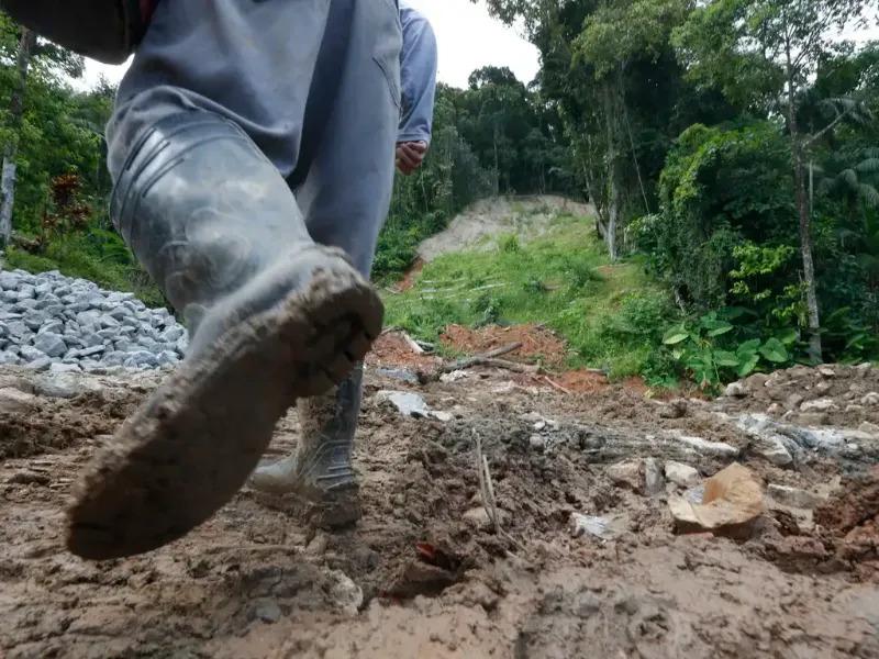 Homem anda em meio a lama causada por desmoronamentos na Vila Sahy