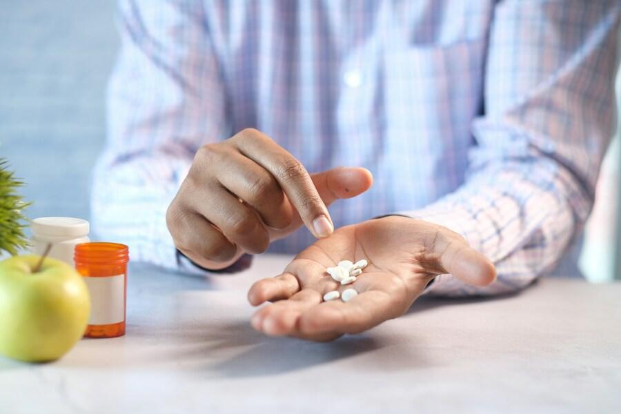 Homem segura comprimidos na mão. Fonte: Unsplash